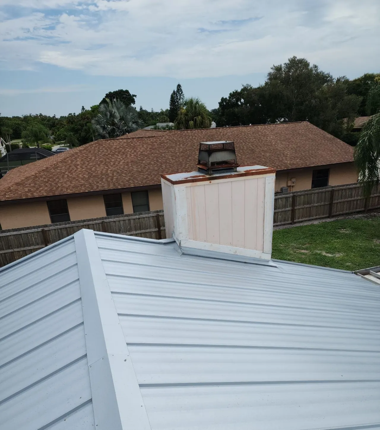 New mill-finish metal roof with clean chimney flashing, re-roofed by Neal Roofing
