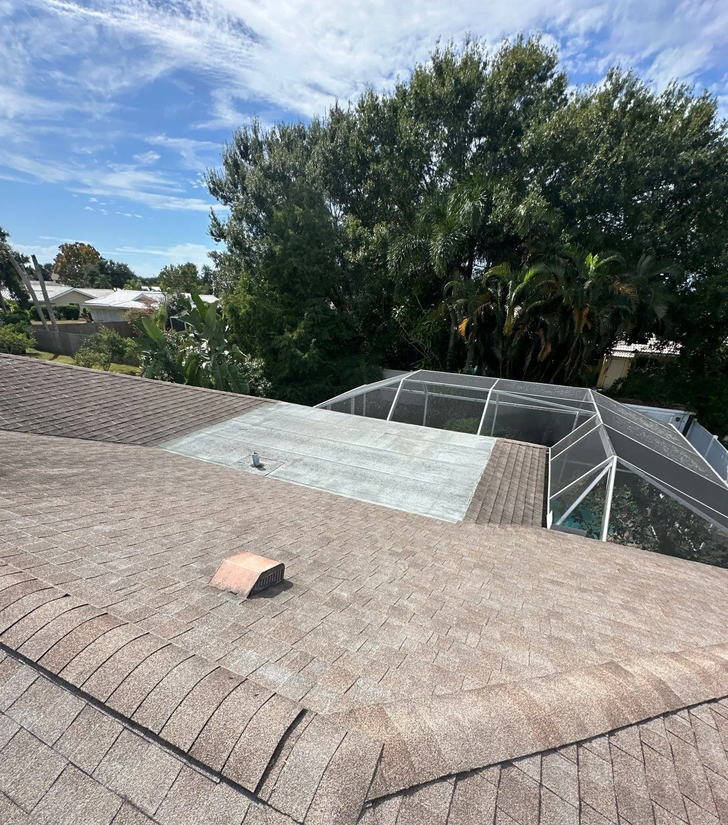 Worn shingle roof and aged flat section beside a pool cage before a Neal re-roof in Sarasota